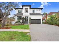 Two-story modern home with white brick exterior, dark gray metal roof, and a paved driveway at 2623 S Parkview St, Tampa, FL 33629