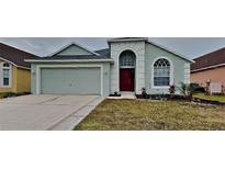 Attractive light teal house with a red door and two-car garage at 29325 Birds Eye Dr, Wesley Chapel, FL 33543