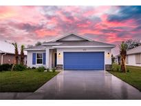 One-story home with blue garage door and landscaped yard; sunset in the background at 425 Rose Apple Cir, Port Charlotte, FL 33954