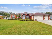 Inviting, red single-Gathering home boasting a well-manicured lawn and a three car garage at 4534 Cozzo Dr, Land O Lakes, FL 34639