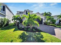 Two-story house with a landscaped front yard, paver driveway, and palm trees at 6137 Voyagers Pl, Apollo Beach, FL 33572