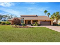 Brick house with brown roof, landscaping, and a large yard at 6151 Silver Oaks Dr, Zephyrhills, FL 33542