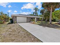 Single-story home with a gray exterior, long driveway, and palm trees at 18292 Robinson Ave, Port Charlotte, FL 33948