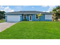 Newly constructed home with light blue exterior, white garage door, and a landscaped lawn at 18400 Tulane Ave, Port Charlotte, FL 33954