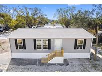 Newly constructed manufactured home with gray siding, and a wooden front porch at 5234 Yellow Pine N St, St Petersburg, FL 33709