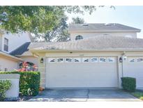 Tan two-story house with a white garage door and landscaping at 2577 Estancia Blvd, Clearwater, FL 33761