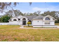 White house with gray roof, arched entryway, and landscaped lawn at 8535 Delaware Dr, Weeki Wachee, FL 34607