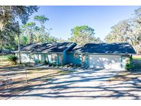 Ranch style home with a two car garage and mature landscaping at 8615 Greenfield Ln, Zephyrhills, FL 33541