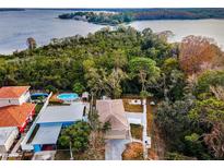 Aerial view of a charming house with a pool, nestled in lush greenery near a lake at 1512 Big Bass Dr, Tarpon Springs, FL 34689