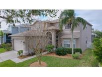 Charming two-story home featuring a well-maintained lawn, mature landscaping, and a welcoming arched entryway at 1632 Gray Bark Dr, Oldsmar, FL 34677