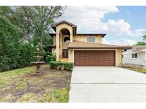 Two-story house with brown garage door, fountain and landscaped yard at 513 Suwanee Cir, Tampa, FL 33606