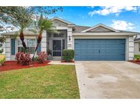 Single-story house with gray siding, blue garage door, and landscaped yard at 5720 107Th E Ter, Parrish, FL 34219