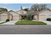 Tan two-story home with brick accents, landscaped lawn, and attached garage at 6432 Remus Dr, New Port Richey, FL 34653