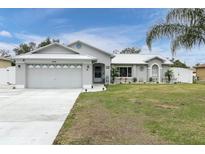 Cute one-story home with gray exterior, attached garage, and landscaped lawn at 10448 Utah St, Spring Hill, FL 34608