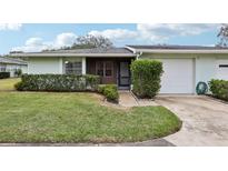 Front view of a light green single-story home with a screened porch and attached garage at 2832 Orange Tree N Cir # B, Palm Harbor, FL 34684