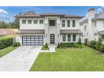 Modern two-story home with a metal roof, two-car garage, and landscaped lawn at 3213 W Fair Oaks Ave, Tampa, FL 33611