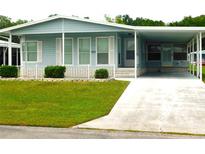 Cute light blue manufactured home with carport and well-manicured lawn at 36819 Kiowa Ave, Zephyrhills, FL 33542