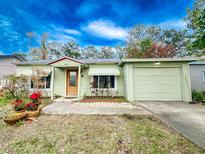 Light green house with a one car garage and nicely landscaped lawn at 1825 San Mateo Dr, Dunedin, FL 34698