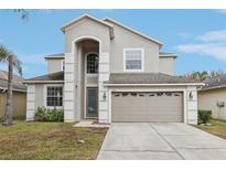 Two-story house with gray siding, two-car garage, and well-manicured lawn at 2915 Trinity Cottage Dr, Land O Lakes, FL 34638