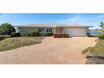 Tan single-story home with a large driveway and mature landscaping at 495 Bath Club N Blvd, North Redington Beach, FL 33708