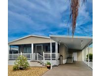 Tan mobile home with carport, covered porch, and landscaped yard at 614 Leisure, Venice, FL 34285