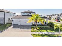 Two-story house with a three-car garage and palm tree landscaping at 7678 Notched Pine Bnd, Wesley Chapel, FL 33545