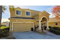 Two-story house with tan exterior, arched entryway, and two-car garage at 8999 Founders Cir, Palmetto, FL 34221