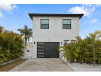 Modern two-story house with a dark gray garage door and landscaping at 16015 Redington Dr, Redington Beach, FL 33708