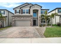 Two-story house with stone accents and a paver driveway at 3071 Marine Grass Dr, Wimauma, FL 33598