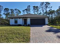 Modern single-story home with a paved driveway and landscaped lawn at 3355 Moncrief Ave, North Port, FL 34286