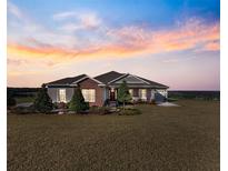 Brick and siding one-story home with landscaped yard at sunset at 36511 Frazee Hill Rd, Dade City, FL 33523