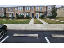 Tan two-story townhome with two-car driveway, landscaping, and sidewalk at 7041 Spotted Deer Pl, Riverview, FL 33569