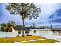 Newly renovated house with a white exterior, landscaped lawn, and attached garage at 7097 Aberfeldy N Ave, St Petersburg, FL 33709