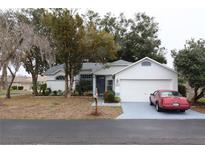 White house with gray roof, two-car garage, and red car parked in driveway at 7923 Leighton Cir, New Port Richey, FL 34654