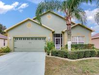 Green house with a two-car garage and palm trees at 9516 Cypress Harbor Dr, Gibsonton, FL 33534