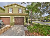 Green two-story townhome with brown garage doors and landscaping at 2803 Santego Bay Ct, Brandon, FL 33511