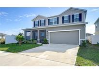 Two-story house with gray siding, dark shutters, and a two-car garage at 35474 Quartz Lake Dr, Zephyrhills, FL 33541