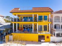 Bright yellow beachfront home featuring private balconies with black railings and a red tile roof at 3702 El Centro St, St Pete Beach, FL 33706