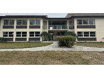 Exterior view of condo building with landscaping and walkway at 4712 Marine Pkwy # 103, New Port Richey, FL 34652