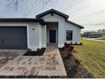 New construction home with gray exterior, paver driveway, and landscaping at 5710 Humkey St, North Port, FL 34291