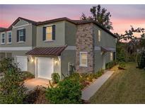 Charming townhome exterior featuring a stone accent wall, well-maintained landscaping, and a covered entrance at 6972 Ripple Pond Loop, Zephyrhills, FL 33541