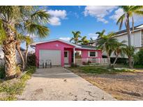 Pink house with garage and tropical landscaping at 129 Wall St, Redington Shores, FL 33708