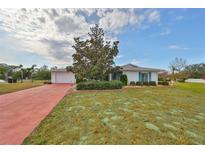 Ranch style home with red brick driveway and mature landscaping at 1807 Pineapple Palm Ct, Sun City Center, FL 33573