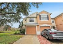 Two-story townhome with attached garage and brick driveway, located by a pond at 2552 Glenrise Pl, Wesley Chapel, FL 33544