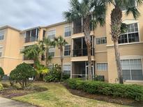 Three-story tan condo building featuring screened in balconies surrounded by lush tropical landscaping with palm trees at 5125 Palm Springs Blvd # 10303, Tampa, FL 33647