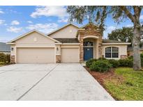 House exterior featuring a three-car garage and stone accents at 6944 Runner Oak Dr, Wesley Chapel, FL 33545