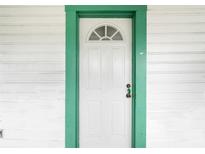 White front door with a green frame and arched window at 710 Seminole St, Clearwater, FL 33755