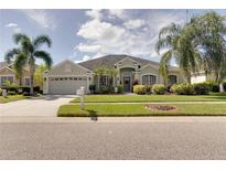 One-story house with light beige exterior, two-car garage, and lush landscaping at 12311 Silton Peace Dr, Riverview, FL 33579