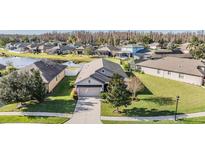 Aerial view of a single-Gathering home with a landscaped yard and a lake in the background at 19724 Post Island Loop, Land O Lakes, FL 34638