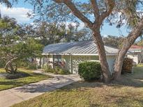 Ranch style home with metal roof, landscaping, and driveway at 2300 Lancaster Dr, Clearwater, FL 33764